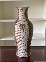 Full front view of tall Imari style porcelain floor vase showing overall shape and pattern composition on a wood surface against a white backdrop.