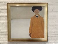 Full frontal view of the framed print depicting a woman in an orange coat and black hat, set against a white and gray background.