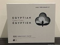 Front view of the white box packaging with text showing KING size and 500 thread count Egyptian cotton sheets branding and cotton logo window showing grey fabric inside.