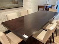 Perspective view of tabletop and undulating edge with upholstered chairs around.