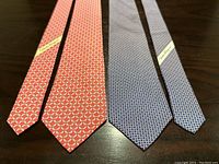 Both silk ties laid flat on a dark wooden surface showing full length and pattern details.