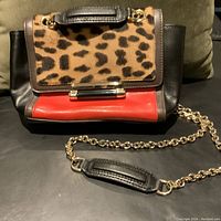 Front view of mini leopard-print leather calf bag with black and red leather panels, gold chain strap with leather shoulder pad.