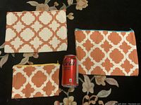 Three fabric pouches of varying sizes and white burnt orange geometric pattern with zipper closures, shown with a soda can for size reference.
