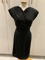 Front view of vintage ESCADA Sport black dress on mannequin, showing wrap-style bodice, cap sleeves, and waistband detail.