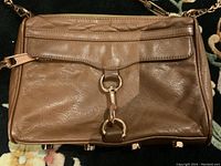 Front view of the brown leather purse showing the flap with clasp closure and rose gold hardware.