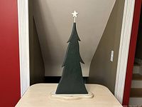 Front view of the handmade wooden Christmas tree against a neutral background, showing the dark green painted tree and natural wood base with white star topper.