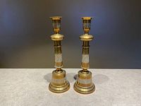 Front view of vintage etched brass candle holders showing their detailed patterns and structure.