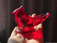 Red translucent glass cardinal art glass bird held in hand, showing body and head details.