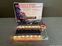 Front view of the light set illuminated, showing 80 colored bulbs arranged in motion with the white plastic base and Santa control figure visible.