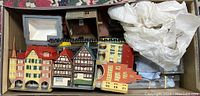 Assorted European town model building facades packed in a box with some protective padding, showing various colorful and detailed miniature buildings.