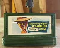 Green Billboard Blinker with vintage Wrigley's Spearmint Gum ad; green plastic base marked 'Standard' with some cracks visible on front.