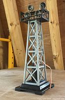 Silver and black Lionel Floodlight Tower with four mounted spotlights on top, metal lattice tower structure, resting on black base with attached wiring.