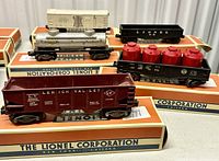 Photo showing five Lionel model train cars in original boxes on a shelf.