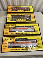 Four Rail King train cars in original yellow and black boxes on a table