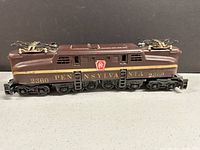 Side profile view showing brown body, gold stripe, PRR keystone shield crest, wheels and chassis