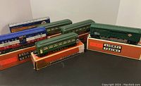 Overview showing six Lionel train cars with original boxes, including green passenger cars and blue freight cars