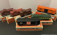 Full lot view showing three brown cabooses, green Pullman car, black and orange New Haven box cars on original boxes.