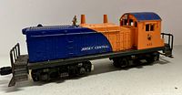 Side view of Lionel Diesel Switcher model 611 painted blue and orange with Jersey Central markings, showing the locomotive's profile and detailing.