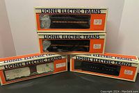 Photo of four Lionel train items in original boxes: two tenders and one milk car in boxes, and a box without visible item.