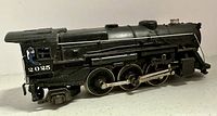 Left side view of the Lionel 2025 steam engine model showing the cab with engineer figure, wheels and detailed pipes.