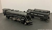 Lionel steam locomotive 665 with New York Central tender shown side by side on a black surface.