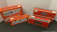 Photo of six original Lionel train car boxes arranged upright and lying flat, showing orange and red box designs.