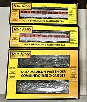 Three boxed Rail King electric train passenger cars, showing detailed packaging and labels