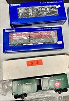 Three boxed and loose industrial HO scale rail cars with visible branding and packaging.