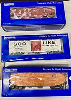 Three Industrial Rail 027 scale model railcars including a New York Central hopper, a Soo Line boxcar, and a Union Pacific reefer car, all in original blue window display boxes.