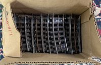 Box with multiple black model train track pieces organized inside, straight sections clearly visible
