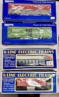 Four model train cars in original boxes: New York Central Pacemaker boxcar, Burlington Northern boxcar, CSX gondola, and Santa Fe lighted caboose.