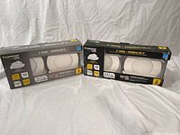 Two boxed sets of Luminus LED 4-inch panel pot lights with built-in junction boxes, unopened and viewed from the front and sides.