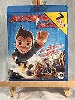 Front cover of the Astro Boy Blu-ray showing the main character flying with other characters and a blue sky background. Text highlights languages French and English.