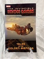 Front cover of The Invincible Iron Man graphic novel showing Iron Man flying with sunset background and bold title text.