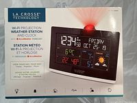Front box of new La Crosse Technology Wi-Fi projection weather station showing main features and a photo of the device with the red projection light on.
