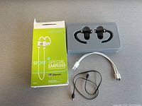 Full set including earbuds in tray, original box, charging cable, and adapter cable all laid on a flat surface.