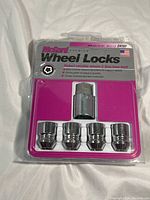 Front of packaging showing four chrome-plated wheel locks and key socket with McGard branding and product info.