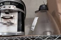 Close-up of the industrial coffee grinder showing metal body, digital display area, and portafilter holder with signs of wear.