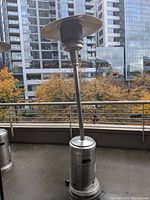 Full view of the Fire Sense outdoor patio heater on a balcony with buildings and trees in background.