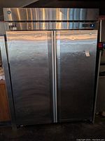 Front view of stainless steel Hoshizaki cooler with two doors, digital control panel on top right, showing dents and surface wear.