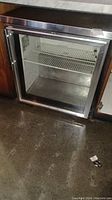 Full view of the industrial refrigerator with glass door showing inside shelves and exterior stainless steel frame.