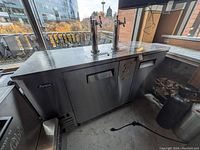 Wide angle showing the full stainless steel kegerator, dual taps, and front doors with recessed handles. Brand ‘Arctica’ on side.