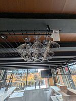View showing twelve clear martini glasses hanging upside down from a metal rack above a bar area.