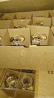 Top view of multiple stemware glasses packed in segmented cardboard box showing stem bases