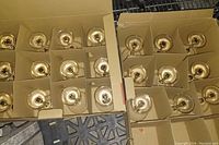 Top-down view of two open cardboard boxes, each containing martini glasses separated by cardboard dividers. Total of 21 glasses visible, arranged in rows.