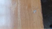 Close-up of the wooden tabletop showing scratches and wear marks.