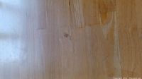 Top view of square wooden table surface showing scratches and wood grain.