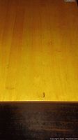 Close-up of wooden table surface showing scratches and wood finish.
