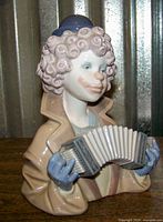 Front and side view of the Lladró figurine showing the clown playing an accordion with detailed pastel colors and glossy finish.