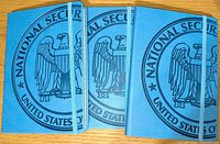 Three blue leather-bound journals with large embossed National Security Agency emblem on covers, elastic bands visible for closure.